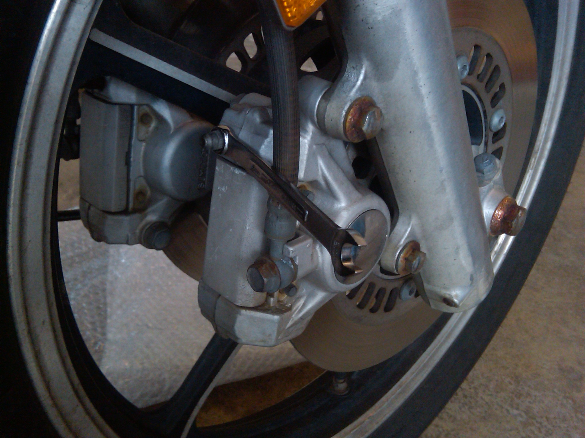 A wrench resting on the bleeder valve.  It is not yet loosened.